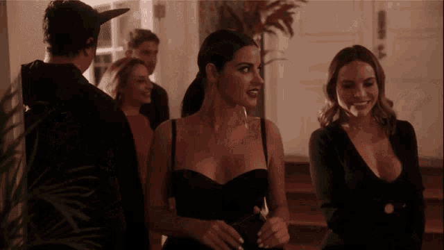 a woman in a black dress is standing next to another woman in a black dress