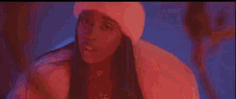 a woman wearing a fur coat and a pink hat is standing in a dark room .