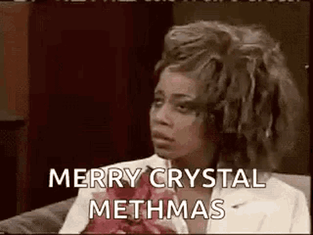 a woman is sitting on a couch with her hair in rollers and saying merry crystal methmas .