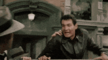 a man in a leather jacket is being held by another man