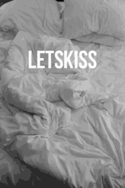 a bed with white sheets and pillows and the words lets fuck written on it