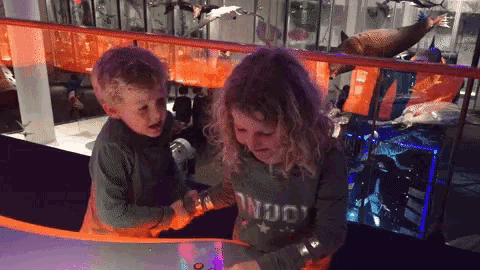 a boy and a girl are playing with a toy and the girl is wearing a sweater that says indo