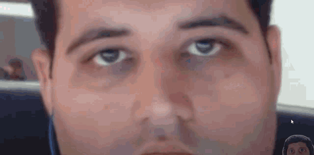 a close up of a man 's face with a woman 's face in the background .