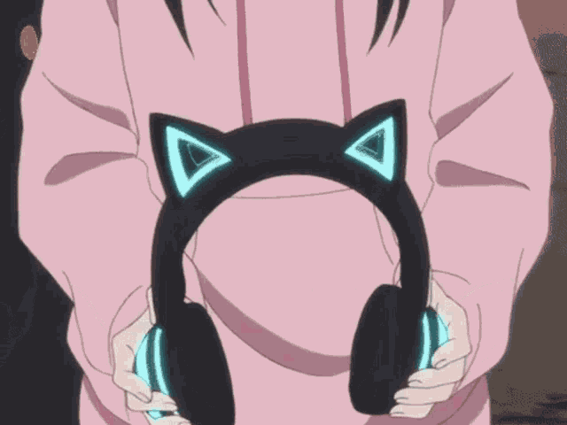 a person wearing a pink hoodie is holding a pair of headphones with cat ears on them
