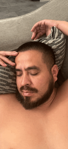 a man with a beard is laying on a bed with his eyes closed