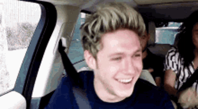 a young man is sitting in the back seat of a car smiling .
