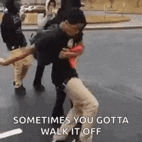 a group of people are dancing on a street and one of them is holding another man 's leg .