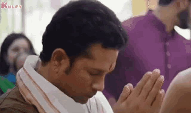 a man is praying in a temple with his hands folded in prayer .