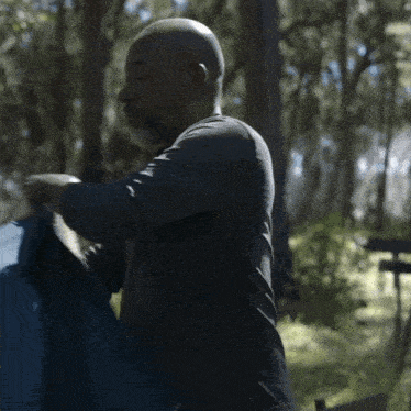 a man in a black shirt is standing in the woods