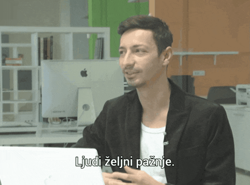 a man sitting in front of an apple computer with the words ljudi zeljni paznje below him