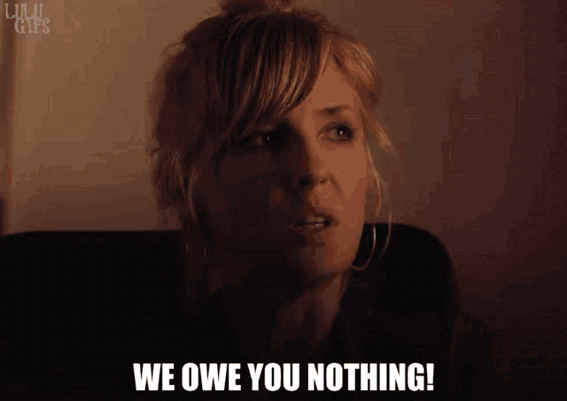 a woman says we owe you nothing in front of a wall