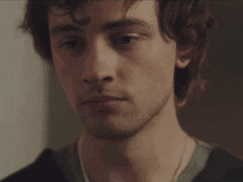 a close up of a young man 's face with a necklace around his neck