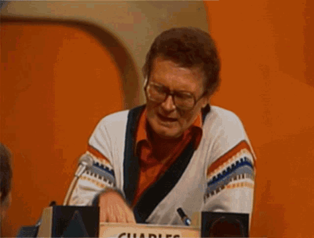 a man sitting at a table with a name plate that says charles on it