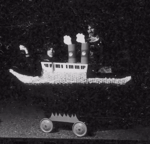 a black and white photo of two people in a boat made out of toilet paper rolls