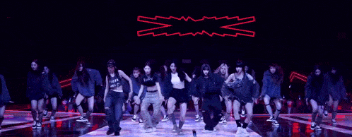 a group of women are dancing on a stage in front of a sign that says x and x
