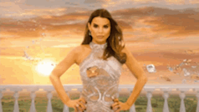 a woman in a white dress is standing on a balcony with her hands on her hips