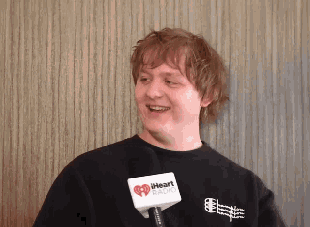a man wearing a black shirt is holding a microphone that says iheart radio