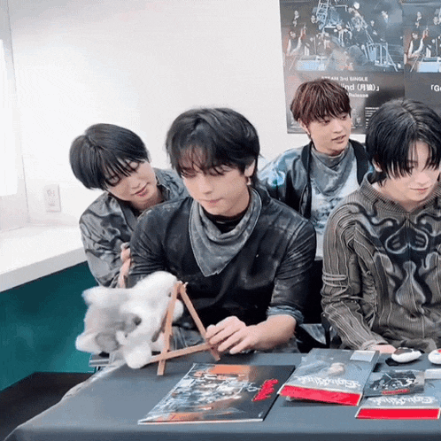 a group of young men are sitting around a table with a poster on the wall that says ' dream 3rd single '