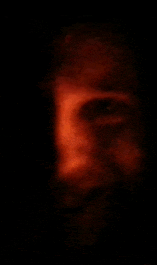 a blurry picture of a man 's face in the dark with a red light coming out of his eyes .