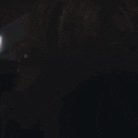 a person is standing in the dark with a light behind them .