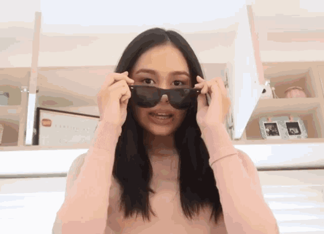 a woman wearing a pink sweater and black sunglasses