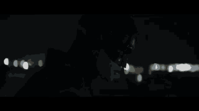 a man is smoking a cigarette in the dark with a blurry background .