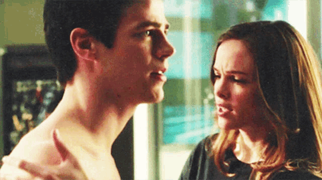 a man and a woman are looking at each other in a room . the man is shirtless and the woman is angry .