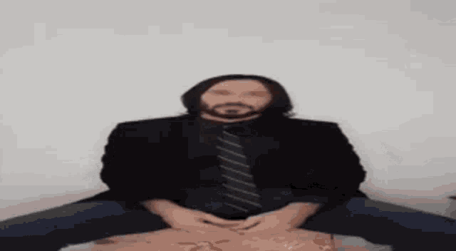 a man in a suit and tie is sitting on a box .