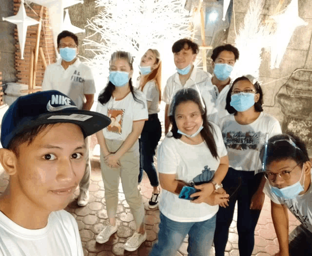 a group of people wearing face masks are posing for a photo with one wearing a nike hat