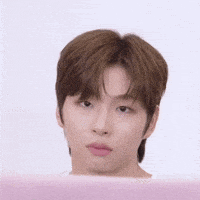 a close up of a young man 's face with a pink background making a funny face .