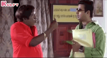 two men are talking to each other in a room and one of them is pointing at the other .
