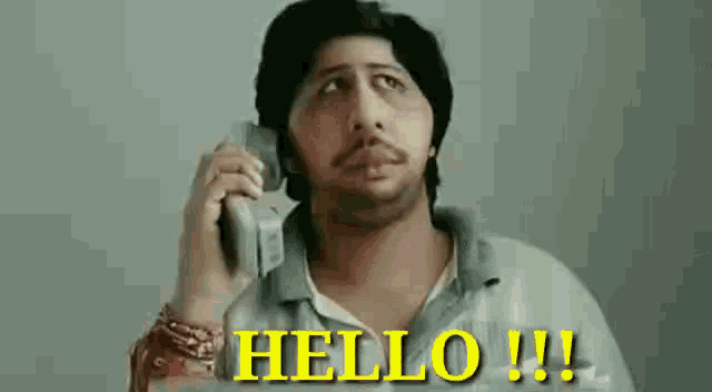 a man with a mustache is talking on a cell phone and saying hello .