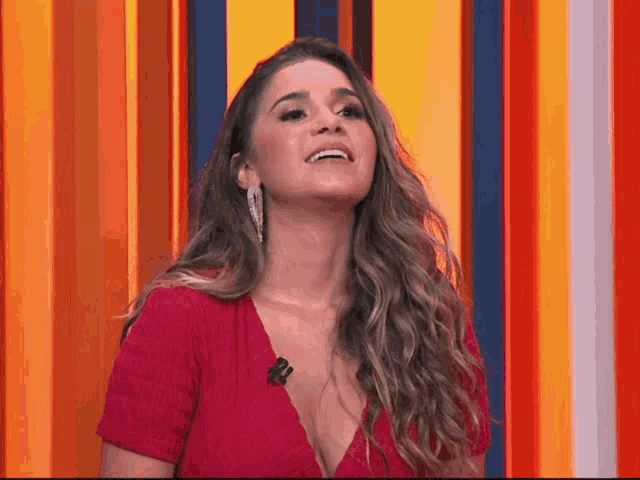 a woman in a red dress is smiling in front of a colorful background