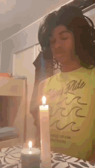 a person wearing a yellow shirt with the word ride on it is holding a lit candle .