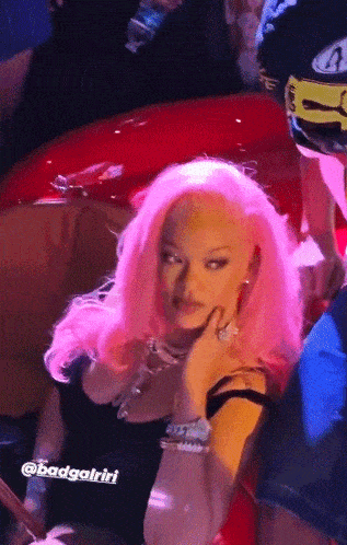 a woman with pink hair is sitting next to a red car