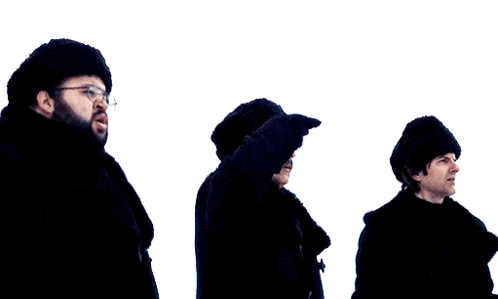three men are standing in the snow wearing black hats and gloves