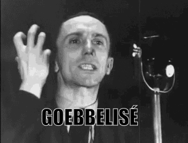 a black and white photo of a man speaking into a microphone with the word goebbelise written on the bottom .