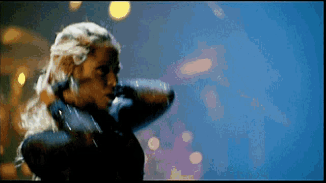 a woman with long blonde hair is standing in a dark room