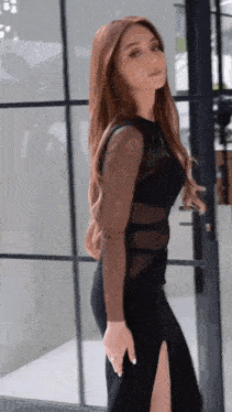 a woman in a black dress is standing next to a glass door .