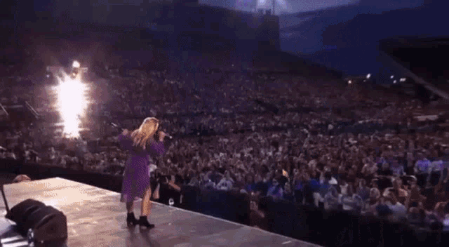 a woman in a purple dress is dancing in front of a drum set with the letters dw on it