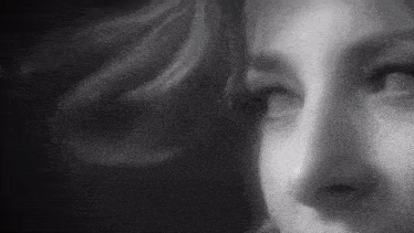 a close up of a woman 's face in a black and white photo looking at the camera .
