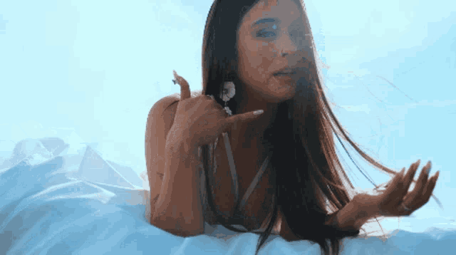 a woman with long hair is laying on a white sheet