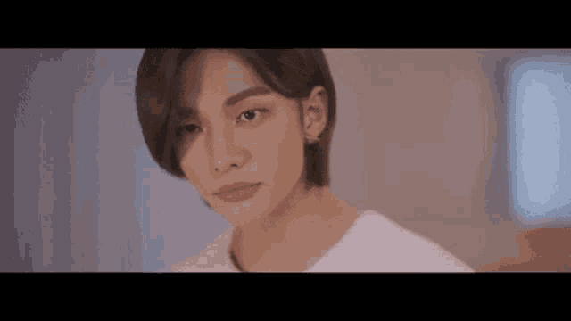 a close up of a young man 's face with short hair and a white shirt .