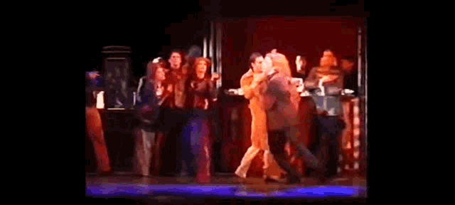 a group of people are dancing on a stage in a theatre .