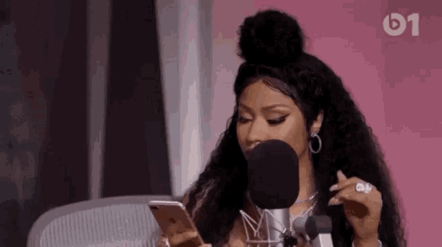 a woman is looking at her phone in front of a microphone .