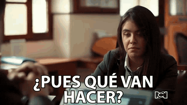 a woman sitting at a desk with the words " pues que van hacer " in white letters