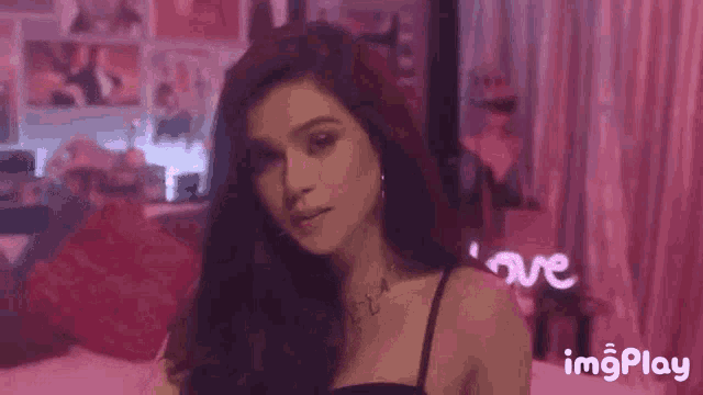 a woman in a black bra is standing in front of a neon sign that says `` love '' .