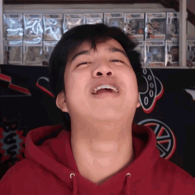 a man wearing a red hoodie is making a face