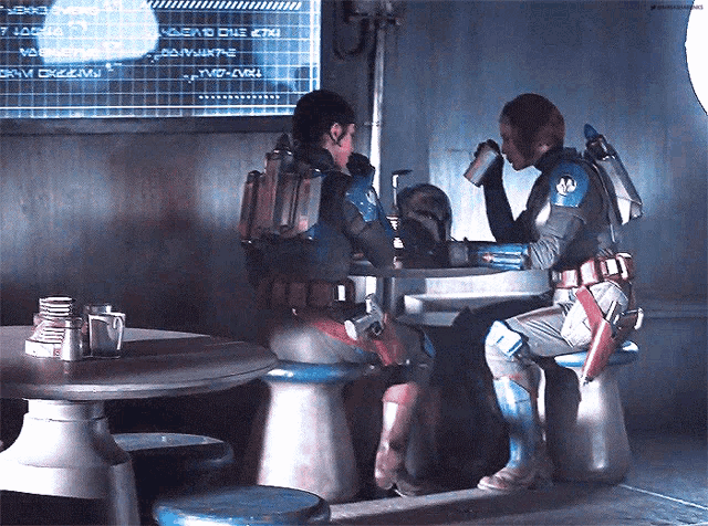 two soldiers are sitting at a table in front of a screen that says ' gnv gnv ' on it