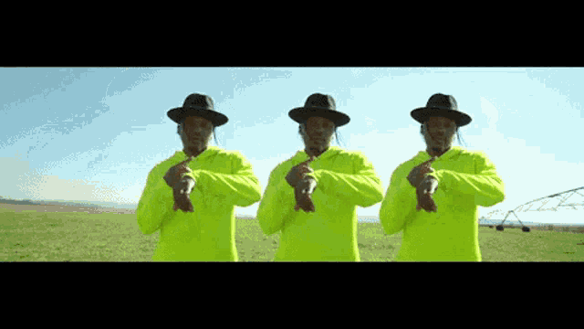 three men wearing hats and neon shirts are standing in a field
